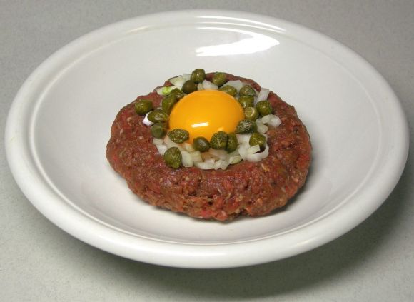 Beefsteak tatar (tartar, tartare) on plate: raw meat and a raw egg yolk. Raw food. Beefsteak tatar (tartar, tartare) on plate: raw meat and a raw egg yolk. Raw food.