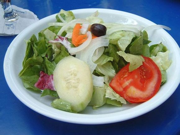 Salad with green leaves, onion, tomato, cucumber, carrot and a black olive. Salad with green leaves, onion, tomato, cucumber, carrot and a black olive.