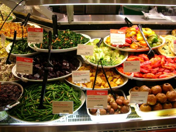 Vegano non significa crudo. Probabilmente qui è tutto cucinato. Vetrina con cibo finito.