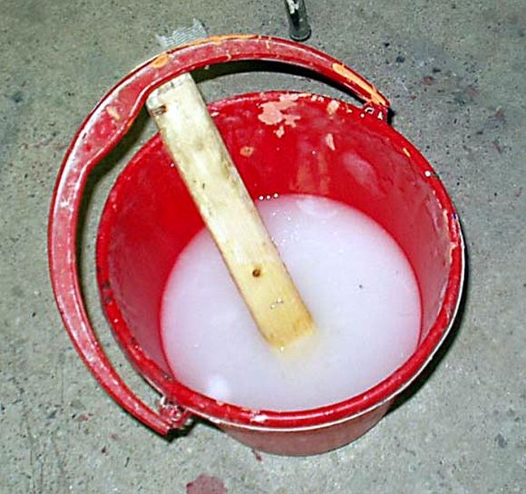 Красное ведро с пастой для обоев из крахмала или эфира целлюлозы.