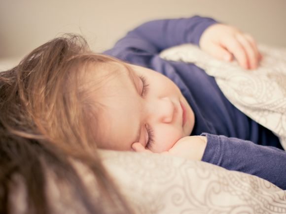 Foto de un niño durmiendo en la cama. Puedes ver el cuero cabelludo, la cara y los brazos.