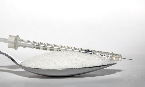 Insulin syringe heaped over a spoon with sugar. Diabetes can not be reduced by this. Insulin syringe heaped over a spoon with sugar. Diabetes can not be reduced by this.
