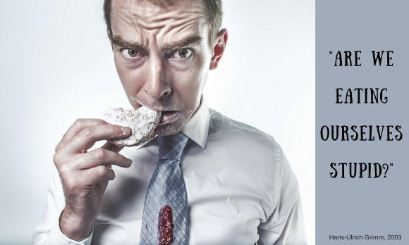 A frowning man bites in a junk food biscuit: are we eating us stupid? A frowning man bites in a junk food biscuit: are we eating us stupid?