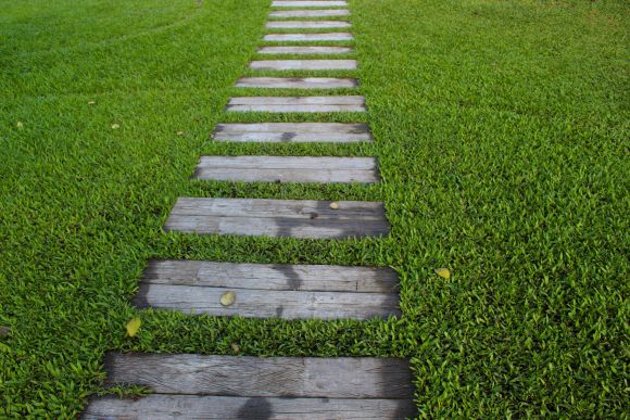 Pares de durmientes de madera en un gran jardín verde como símbolo de nuestro viaje de la vida.