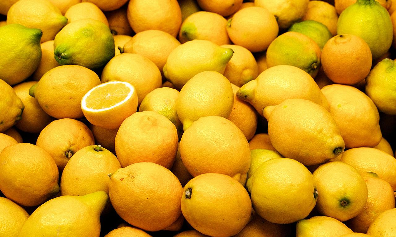 Ganze Zitronen aufgehäuft, eine davon aufgeschnitten.