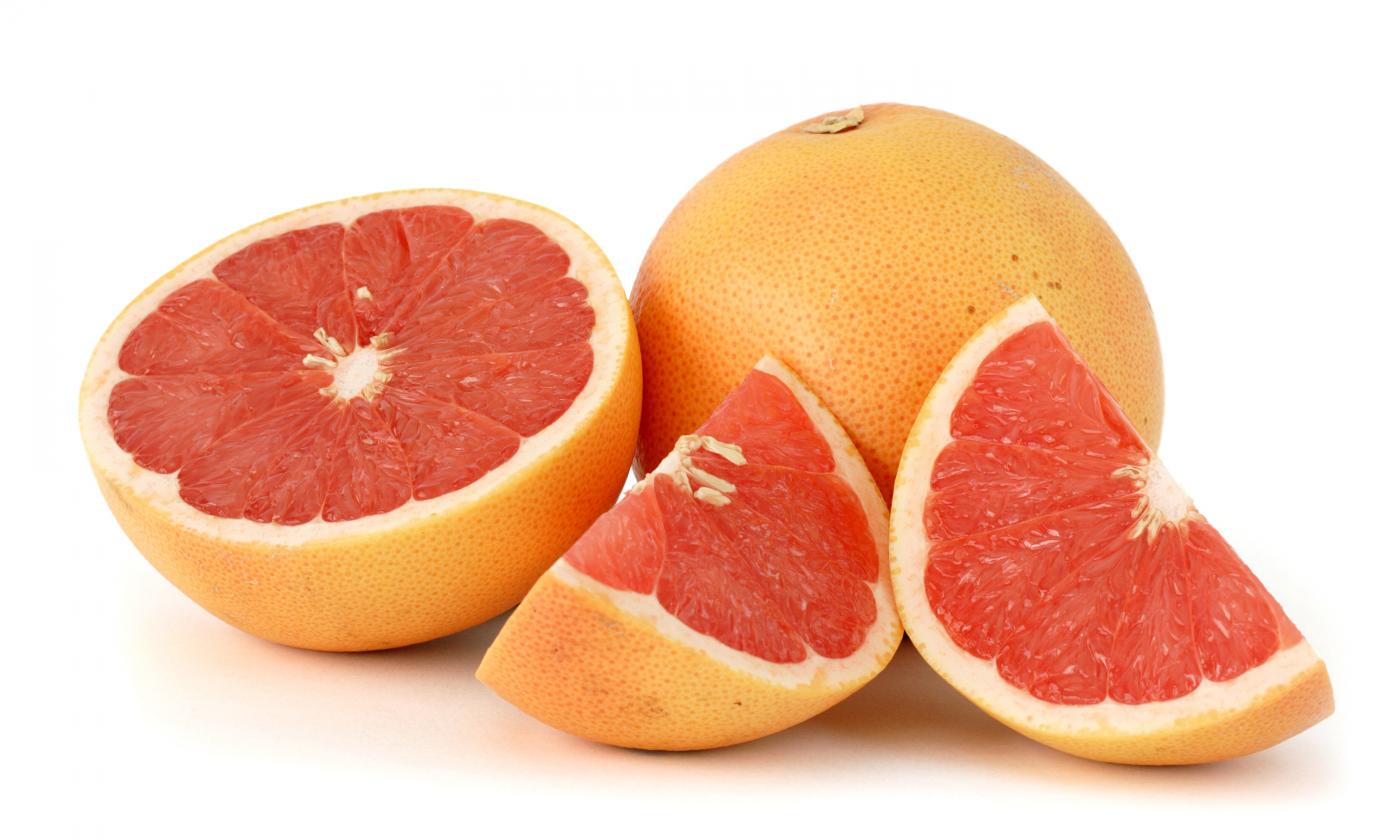 One sliced and one whole grapefruit with red pulp. One sliced and one whole grapefruit with red pulp.