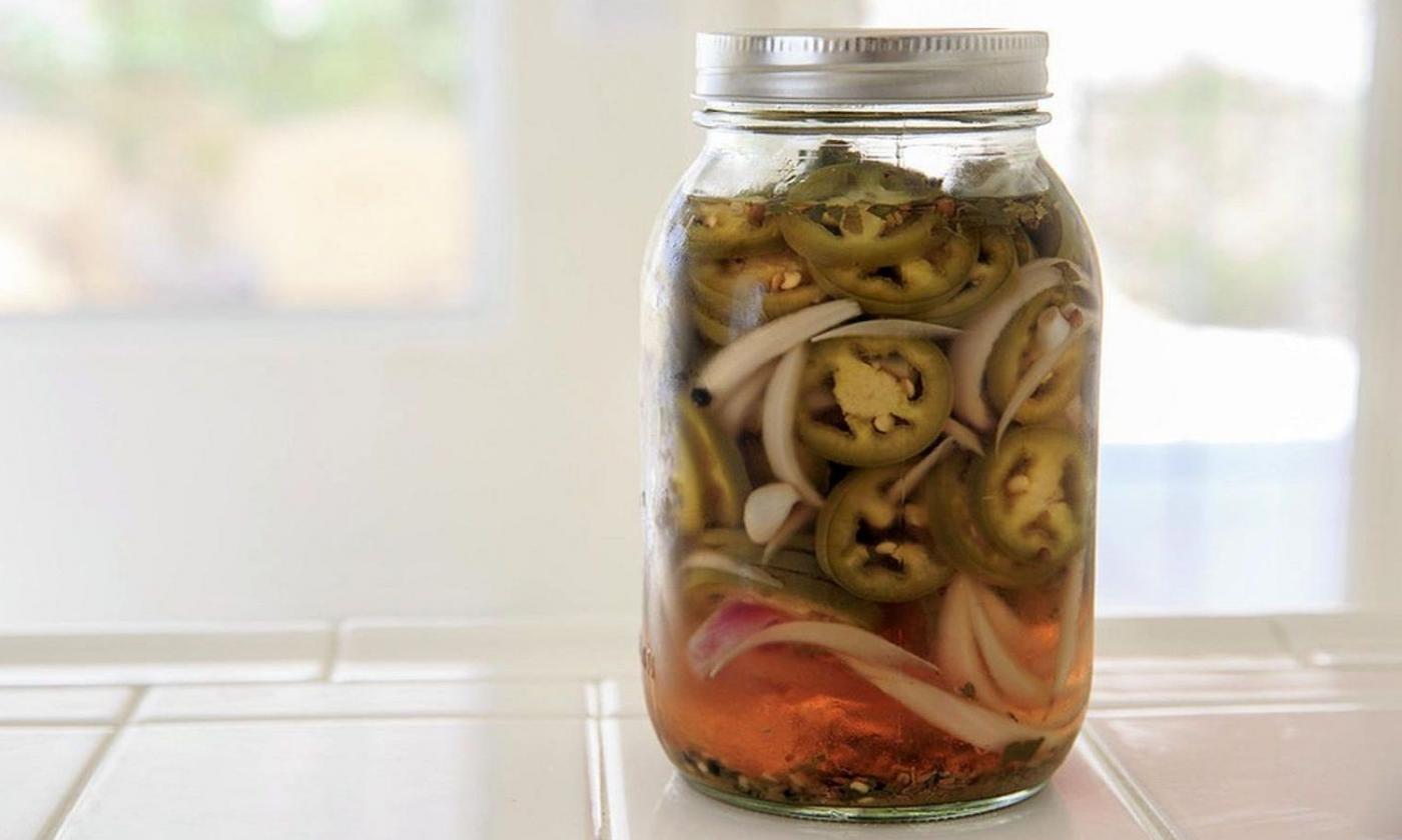 In ein Einmachglas mit Schraubverschluss eingelegte Jalapeños. In ein Einmachglas mit Schraubverschluss eingelegte Jalapeños.