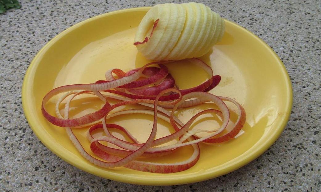 Mela, cruda, sbucciata su un piatto. Accanto a lui, le bucce. Mela, cruda, sbucciata su un piatto. Accanto a lui, le bucce.