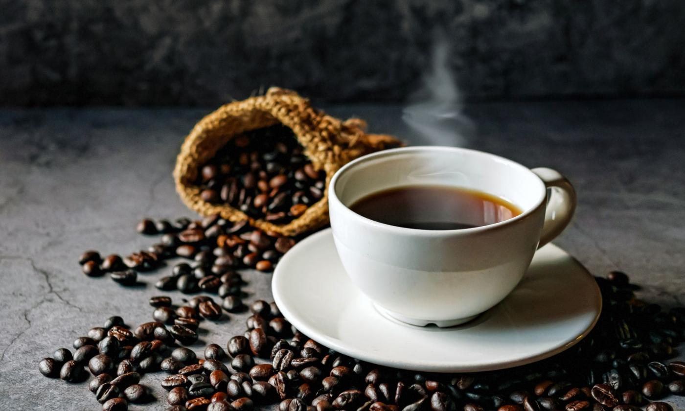 Kaffee - Coffea arabica - in weisser Porzellantasse, Kaffeebohnen drum herum liegend. Kaffee - Coffea arabica - in weisser Porzellantasse, Kaffeebohnen drum herum liegend.