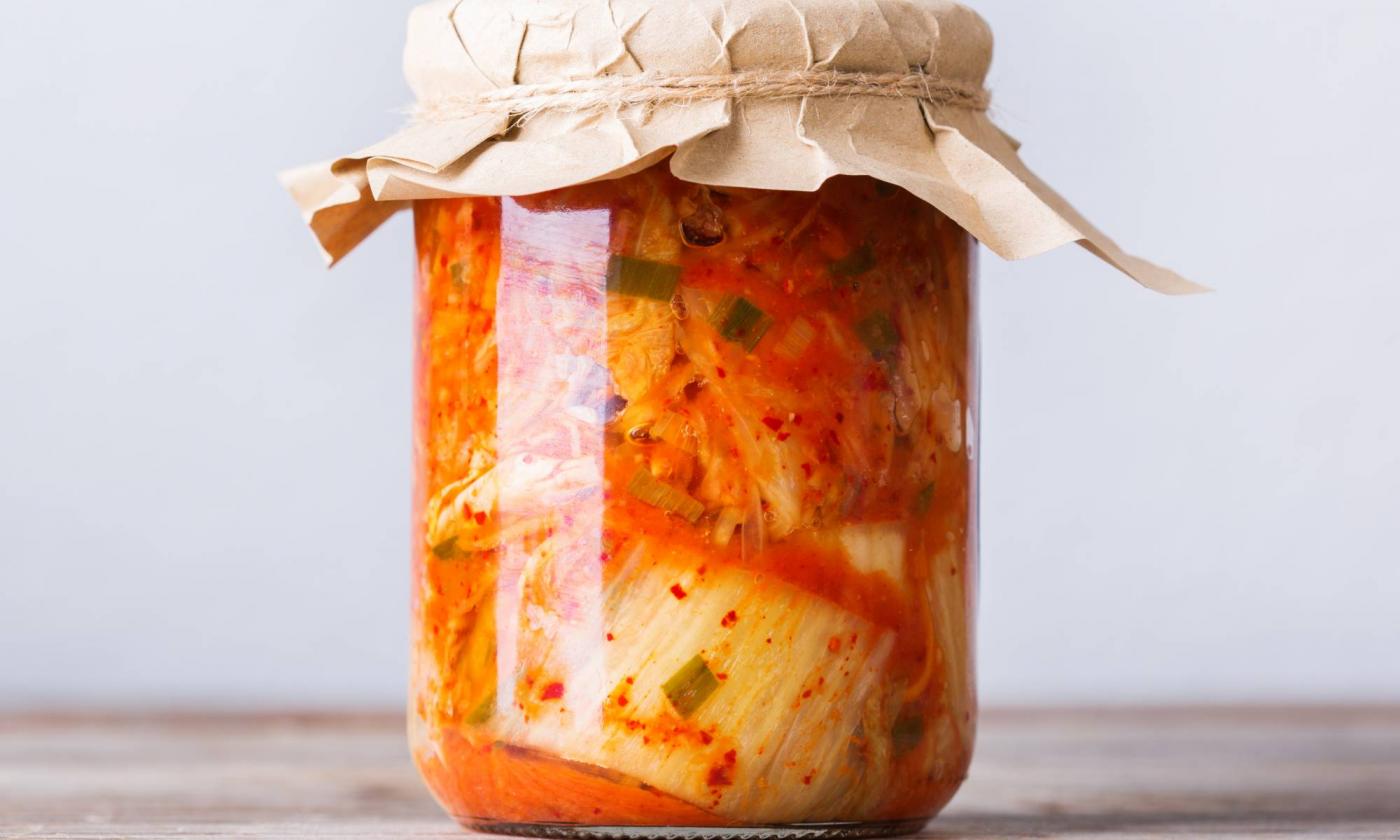 Домашний традиционный корейский салат кимчи из капусты в стеклянной банке на деревянном столе. Домашний традиционный корейский салат кимчи из капусты в стеклянной банке на деревянном столе.