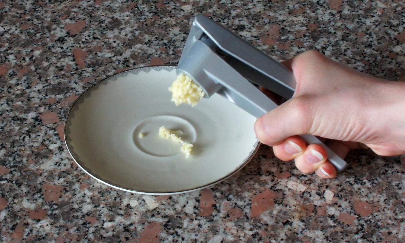 Crush the baked garlic cloves in a garlic press