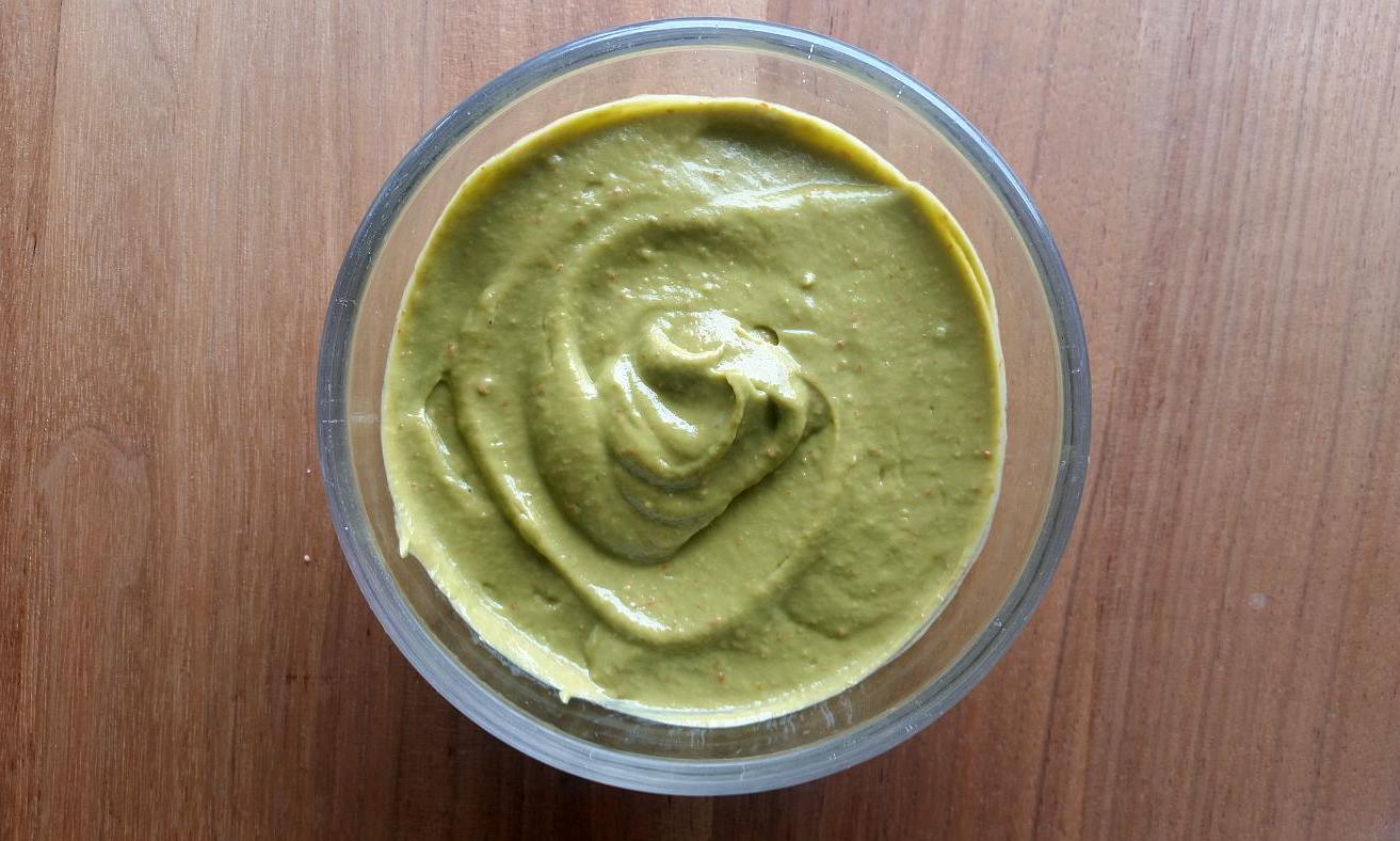 Vegan raw food avocado garlic cream in glass bowl seen from above.