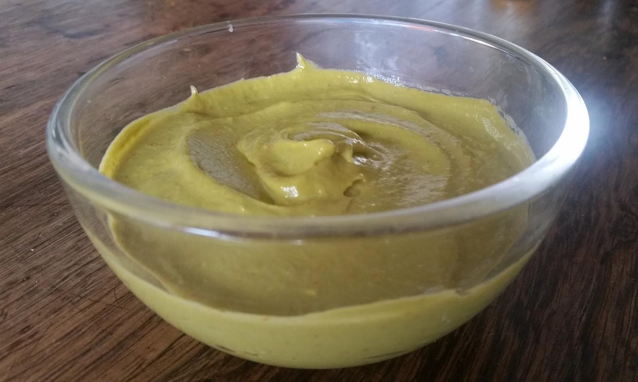 Variation of vegan raw food avocado garlic cream seen in glass bowl sideways.