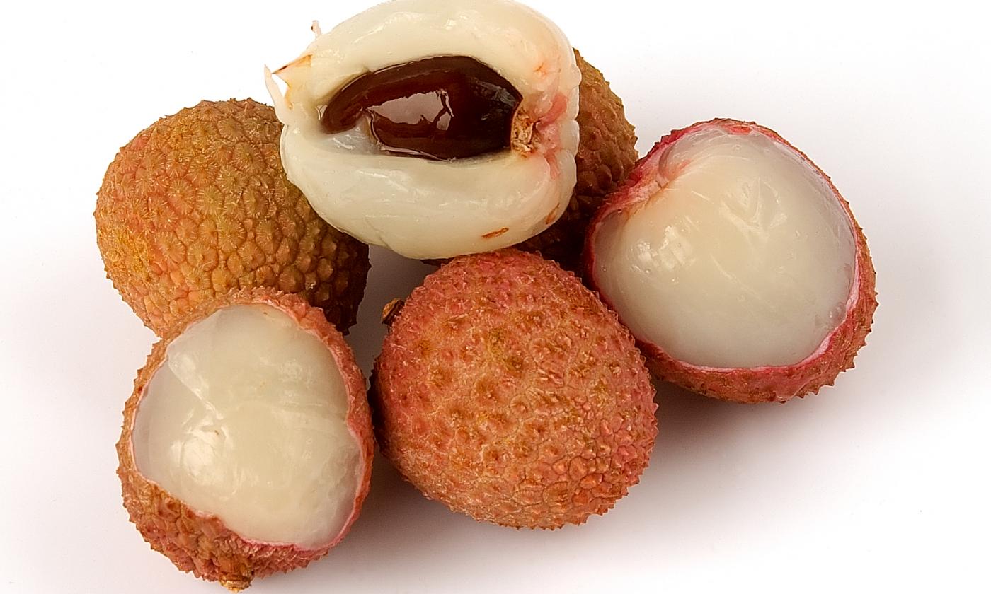 Litchi crudi e parzialmente aperti (Litchi chinensis) su sfondo chiaro.