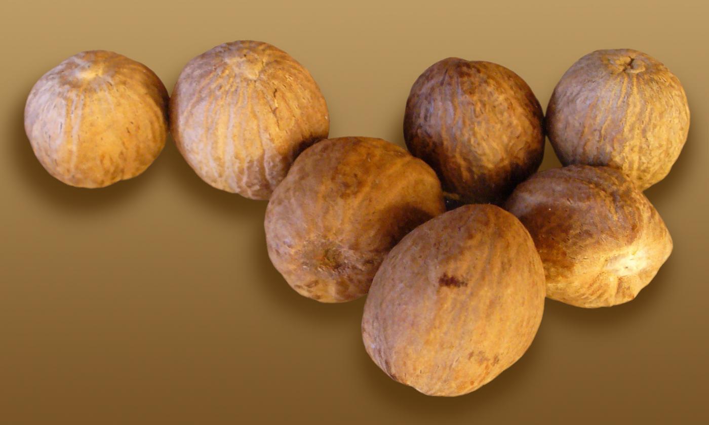 Семь цельных мускатных орехов (Myristica fragrans), лежащих на столе.