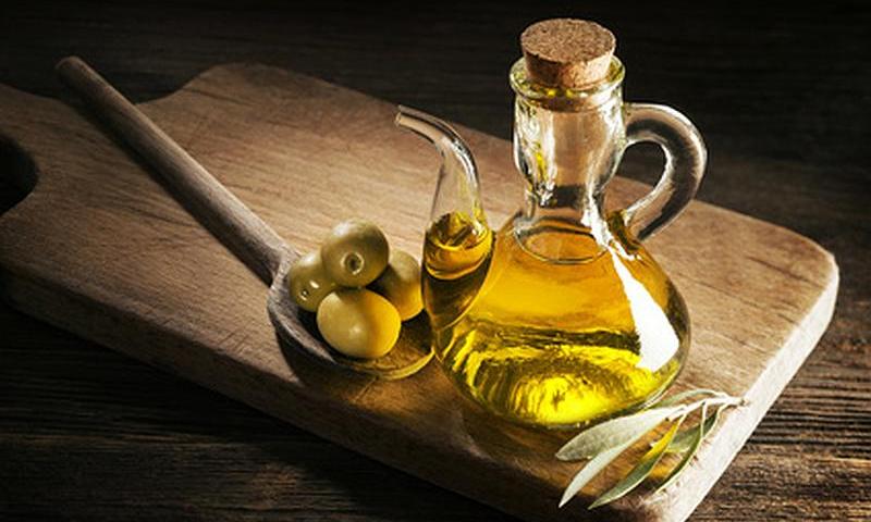 Aceite de oliva en jarra de vidrio en el tablero de madera. Aceite de oliva en jarra de vidrio en el tablero de madera.