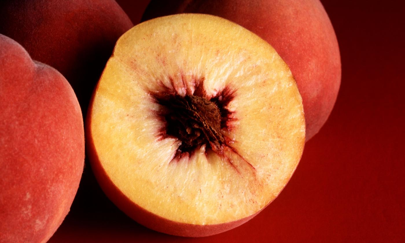 Nectarine halved (peach — Prunus persica) with pit, which is usually in the shape of a sphere.