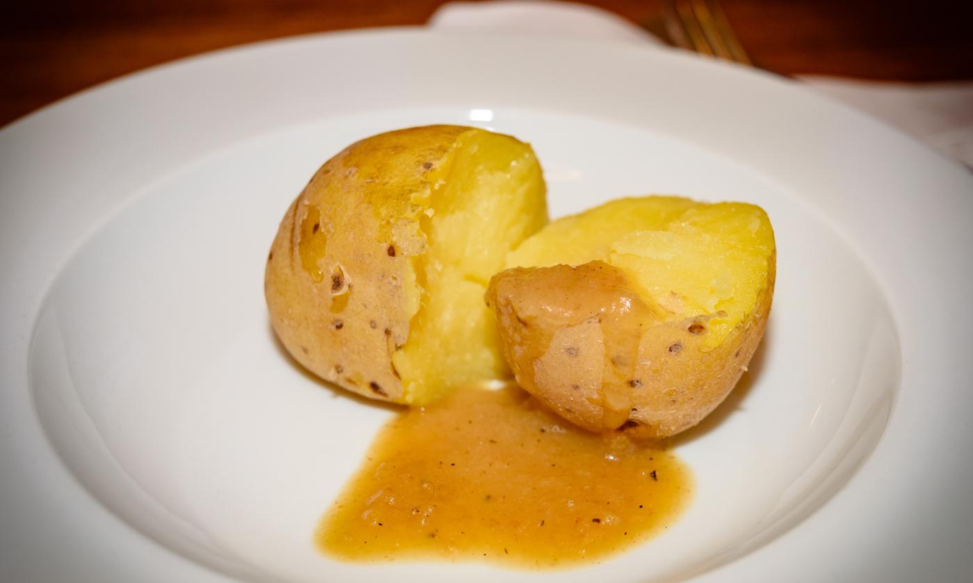 Ready-made "Simple vegan gravy" with a boiled potato on a white plate.
