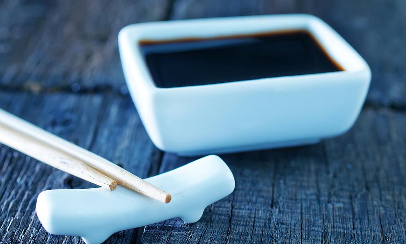 Soy sauce (Genen Shoyu), low salt in square white ceramic bowl with chop sticks next to it. Soy sauce (Genen Shoyu), low salt in square white ceramic bowl with chop sticks next to it.