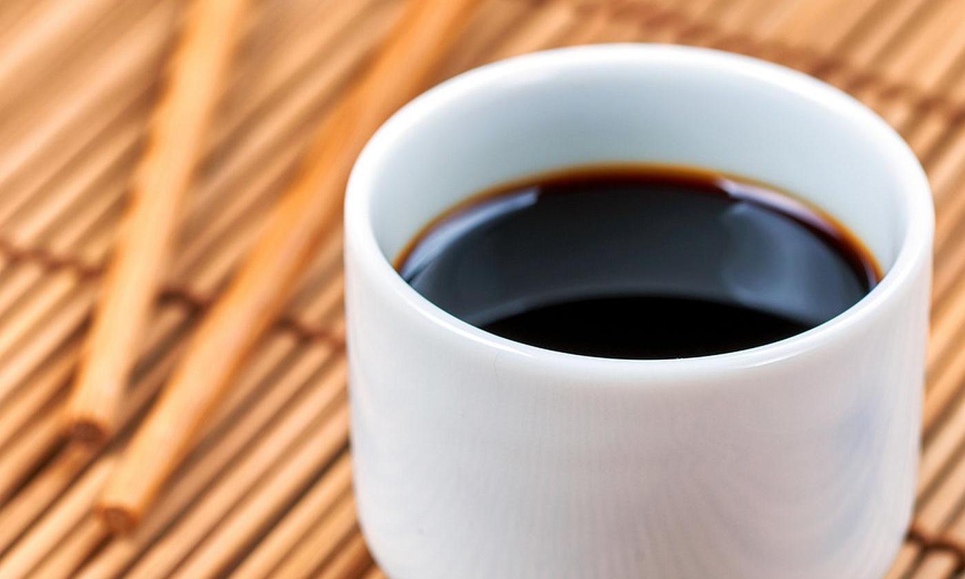 Soy sauce (shoyu) in white cup without handle on bamboo mat. Soy sauce (shoyu) in white cup without handle on bamboo mat.