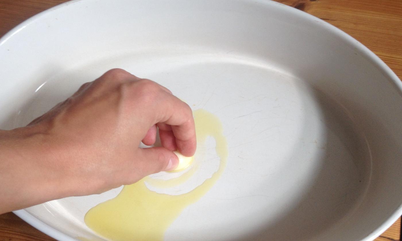 Ungere il piatto con olio e aglio per preparare «Patate al forno con rosmarino e crema di soia».