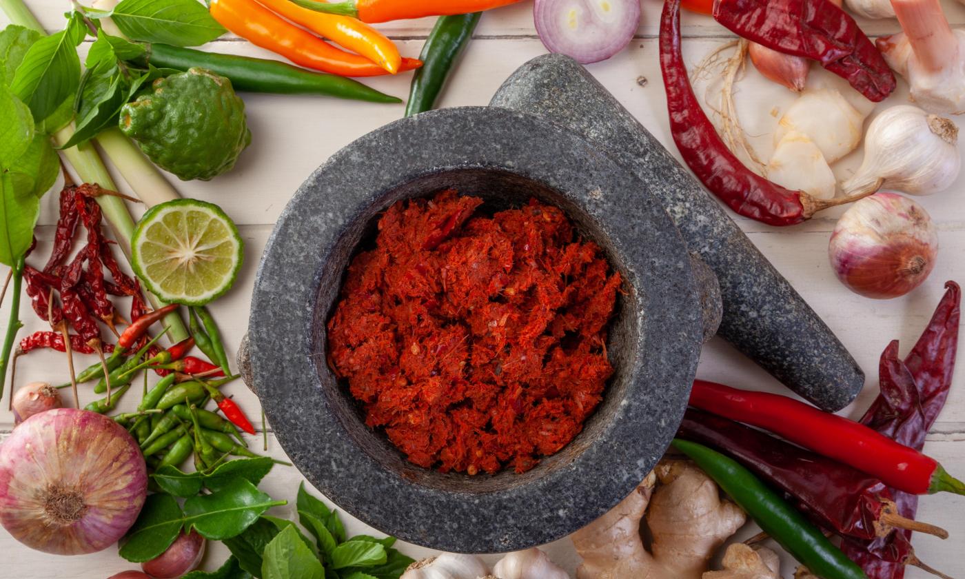 Red Thai curry paste with ginger and kaffir lime leaves - ingredients next to it.