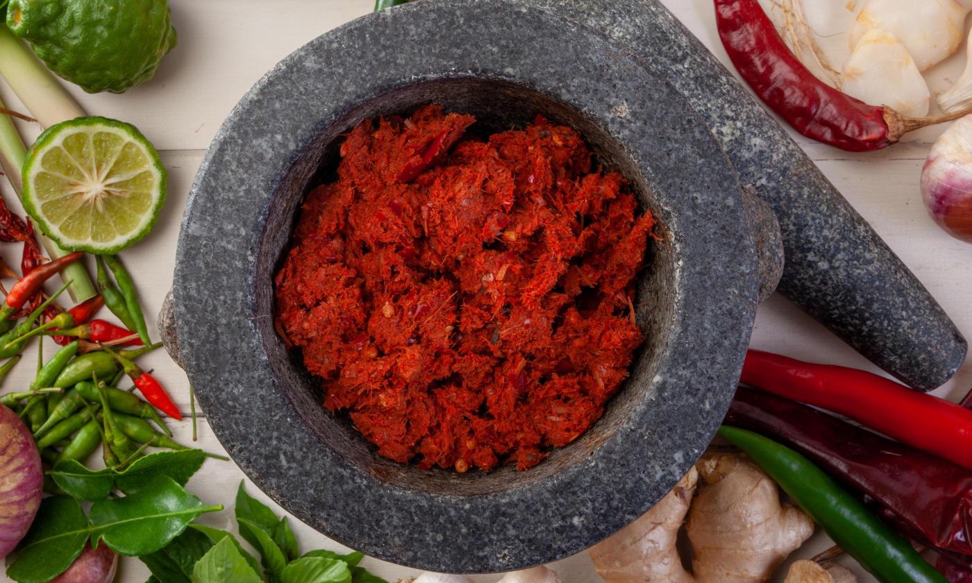 Red Thai curry paste with ginger and kaffir lime leaves and some ingredients alongside.