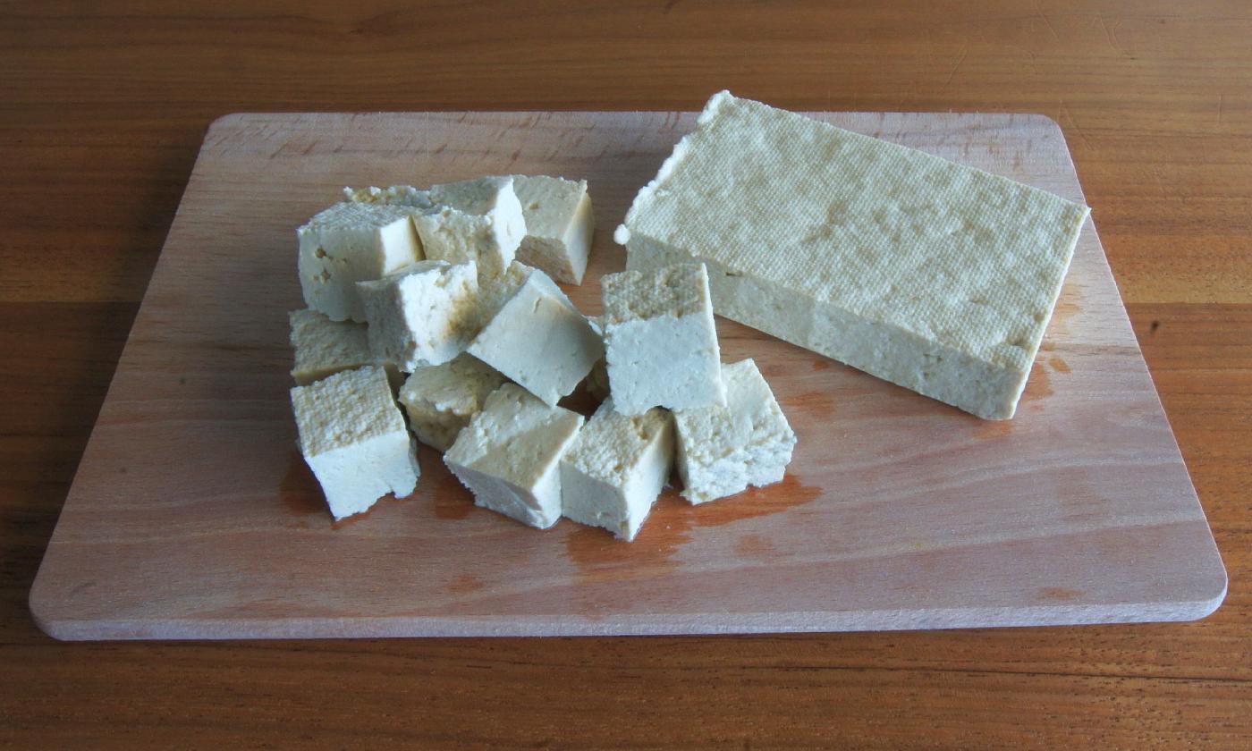 A block of tofu and tofu slices on a cutting board. Tofu has a very neutral flavor and works well as a carrier for many different flavors. A block of tofu and tofu slices on a cutting board. Tofu has a very neutral flavor and works well as a carrier for many different flavors.
