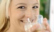 Frau trinkt Hafermilch aus Trinkglas.