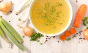 Caldo de verduras bajo en sal con verduras troceadas en un cuenco blanco.