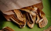 Stark getrocknete, deshalb lang haltbare, längs geschnittene Bananen in bräunlicher Papiertüte.