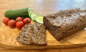 Rezeptbild "Ballaststoffreiches Vollkornbrot mit Walnüssen", angeschnitten neben Gurken und Tomaten.