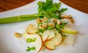 «Ensalada de rábanos crudivegana con manzana y aliño de lima» terminada sobre un plato blanco.