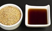 Кунжутное масло из поджаренных семян - Sesamum indicum - в белой чашке, слева светлые семена кунжута
