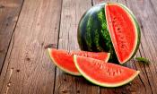 Wassermelone, roh - Citrullus lanatus - auf dunklem Holz, aufgeschnittene Frucht.