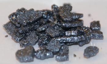 Iodine crystals, iodine in crystalline form with grey background.