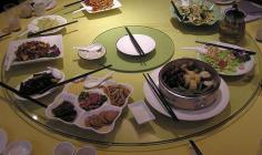 Runder Tisch in China mit verschiedenen Rezepten auf Tellern und anderen Unterlagen.