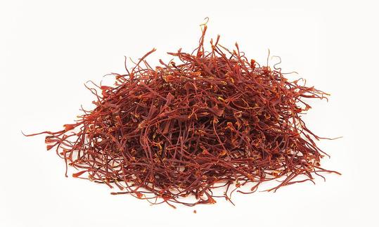 A pile of reddish brown saffron threads (Crocus sativus) on a light background.