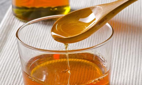 Idromele come dolcificante. Mead in un bicchiere con un cucchiaio di legno per mostrare la sua consistenza simile al miele.