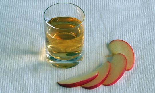 Vaso con vinagre de manzana: el vinagre de manzana se compone de agua, ácido acético y varios minerales. También sirve como remedio curativo natural. Vaso con vinagre de manzana, compuesto por agua, ácido acético y varios minerales.