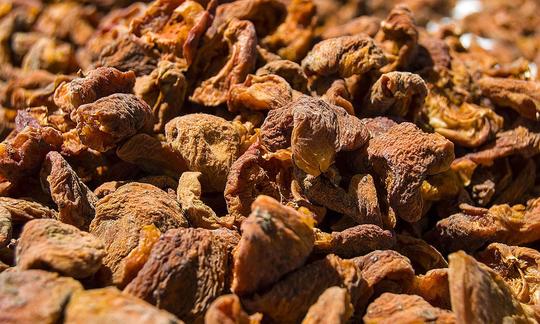 Apricot dried, raw, no sulfur - Prunus armeniaca: brown, not red-orange are apricots if they are dried without sulfur. Image shows a pile of dried and unsulphurized apricots.