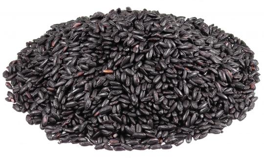 Untreated, dried black wholegrain rice piled up to a pile on a white background.