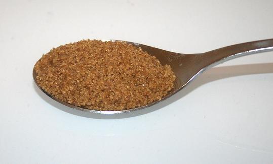 Esslöffel gehäuft mit braunem Zucker auf weisser Tischoberfläche. Esslöffel gehäuft mit braunem Zucker auf weisser Tischoberfläche.
