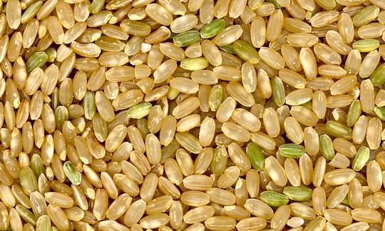 Raw whole grain rice grains on a pile. Certain grains are slightly green because they are less ripe. Raw whole grain rice grains on a pile. Certain grains are slightly green because they are less ripe.