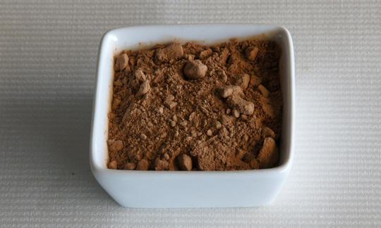 La algarroba en polvo, que se obtiene del fruto del algarrobo, es una buena alternativa al cacao. No contiene mucha grasa, es nutritiva y tiene un sabor dulce. Carruba in polvere in una piccola ciotola quadrata bianca.