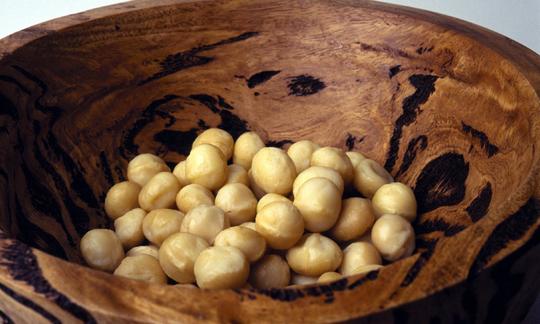 Macadamia, raw - Macadamia integrifolia, M. tetraphylla, cracked, in dark brown bowl. Macadamia, raw - Macadamia integrifolia, M. tetraphylla, cracked, in dark brown bowl.