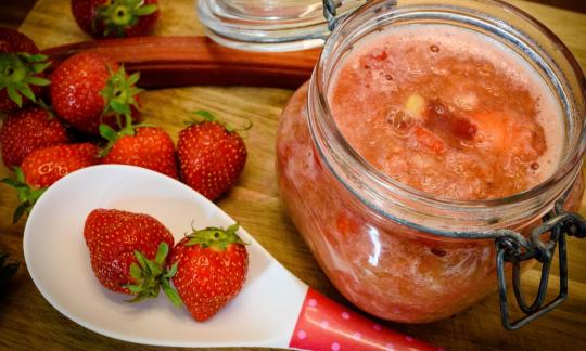 Fertig zubereitetes "Zuckerfreies Rhabarber-Erdbeerkompott mit Banane" auf braunem Holztisch.