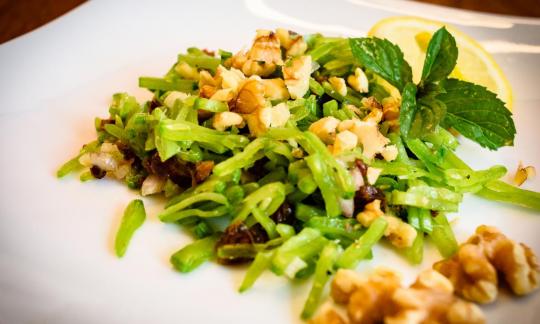 Ready-made "Raw sugar snap pea salad with walnuts and dates" on a white plate.