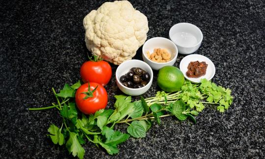 Ingredienti per preparare «Tabbouleh di cavolfiore con olive ed erbe aromatiche» finito e servito. Senza utensili da cucina.