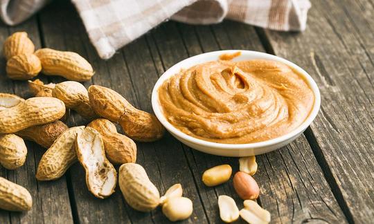 Peanut butter, coarse-grained, without salt in a white plate, peanuts in shell and open. Peanut butter, coarse-grained, without salt in a white plate, peanuts in shell and open.